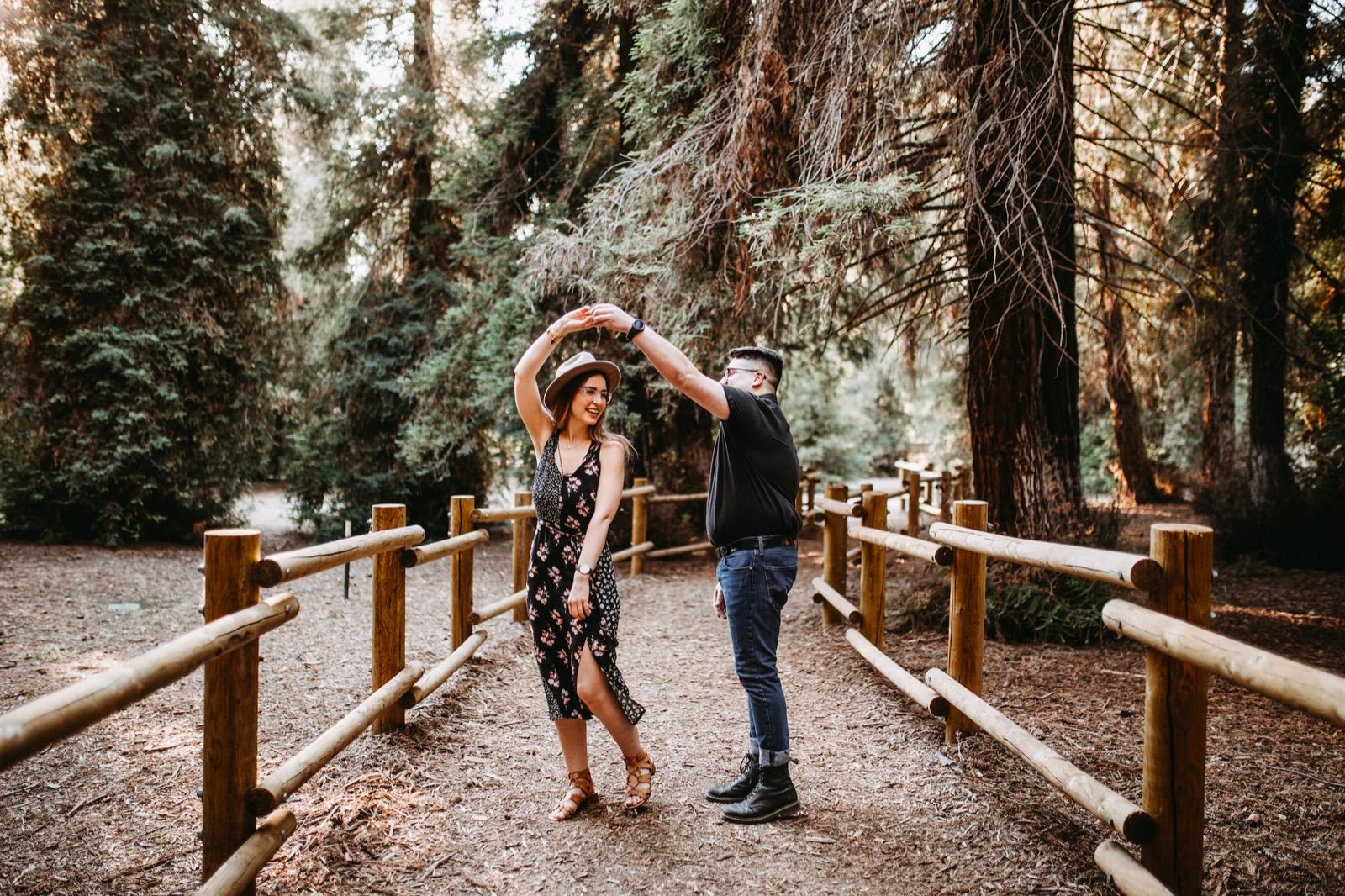 A couple dancing on a wooden path among redwood trees